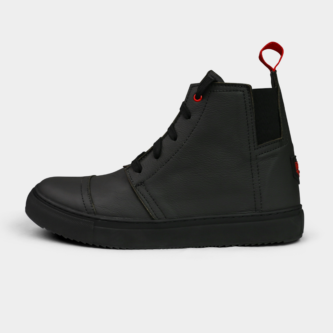 A side-angle product shot of a pair of black high-top shoes, placed side-by-side. The shoes are made of black leather, with black laces and a thick black sole. A bright red loop is attached to the back of each heel. The shoes have a sleek, modern design, and they are on a solid light gray background.